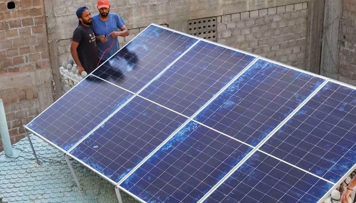 Technicians work on solar panels installed on the roof of a house in Karachi. — Reuters/File