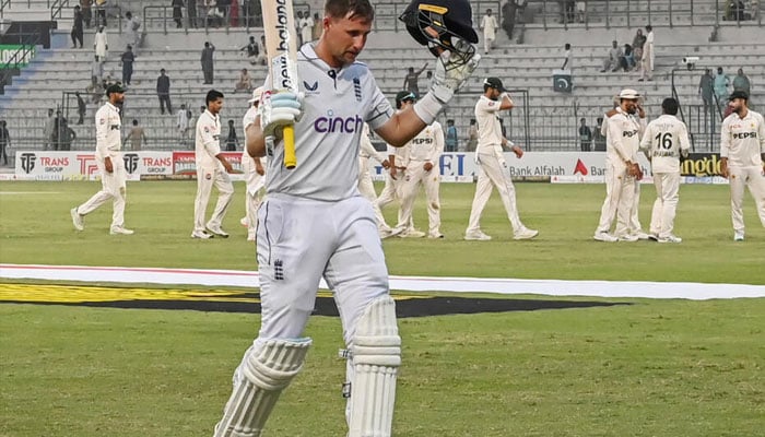 Englands Joe Root walking off the field his bat and helmet raised on Ocotober 9, 2024 in Multan.— AFP