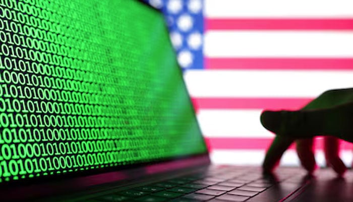 A hand is seen on a laptop with binary codes displayed in front of the USA flag in this illustration taken, August 19, 2022. — Reuters