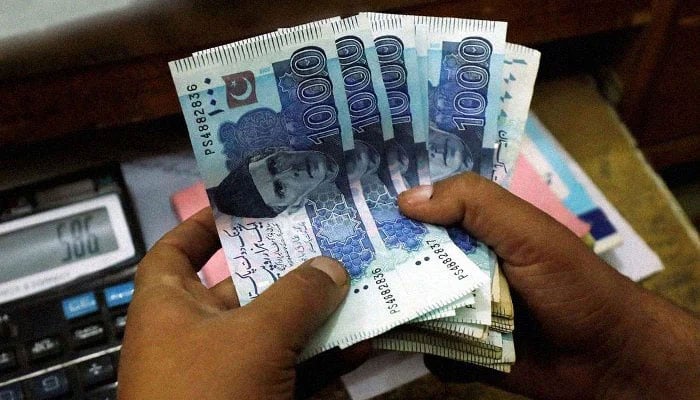 A man is seen holding Pakistani currency notes. — APP/File