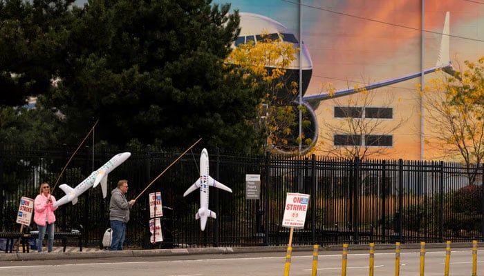 Boeing workers Maria Hamshaw and Tim Mattingly, who are siblings, hold inflatable airplanes on a picket line near the entrance to a Boeing production facility in Renton, Washington, US on October 11, 2024. — Reuters