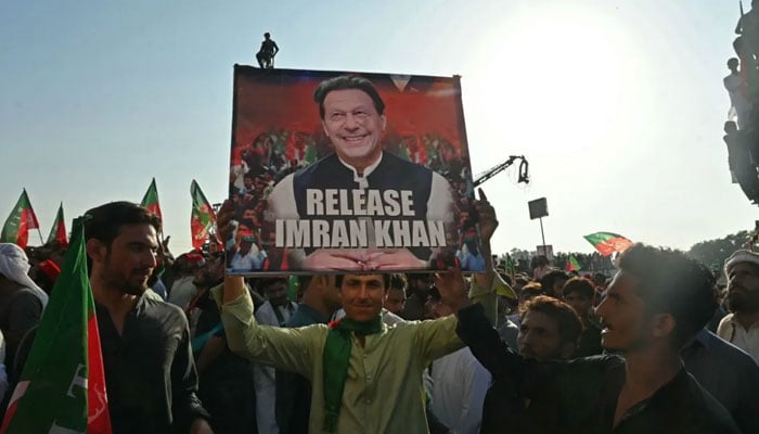 PTI workers hold party founder Imran Khans portrait during a protest. — AFP/File