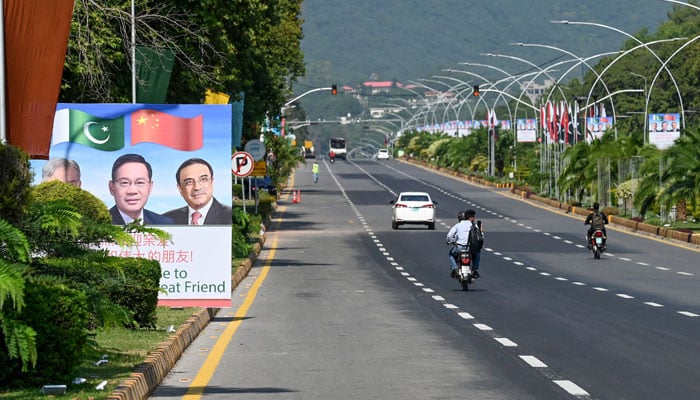 Commuters ride past a billboard featuring images of Chinas Premier Li Qiang (C), Pakistans Prime Minister Shehbaz Sharif and President Asif Ali Zardari (R) ahead of the Shanghai Cooperation Organisation (SCO) summit in Islamabad on October 13, 2024. — AFP