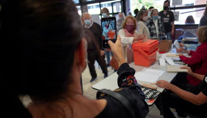 A woman photographs her mother casting a vote in a referendum on whether or not to eliminate 135 articles of the Urgent Consideration Act, at a polling station in Montevideo, Uruguay March 27, 2022. — Reuters