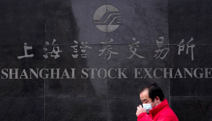 A man wearing a mask walks by the Shanghai Stock Exchange building at the Pudong financial district in Shanghai, China, February 3, 2020. — Reuters