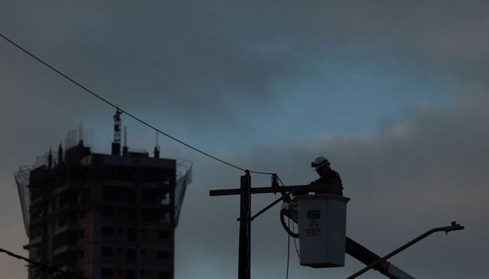 A man works on a pole to restore electricity after a storm knocked down power cables in Sao Paulo, Brazil November 6, 2023. — Reuters