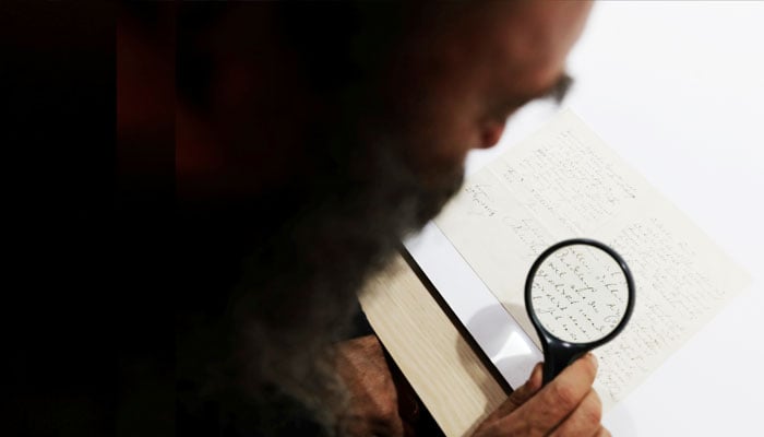 A man looking at a document with a magnifying glass.— Reuters/file