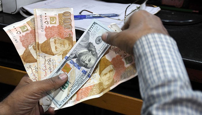 A foreign currency counts Pakistani rupee notes at a shop in Karachi, on March 2, 2023. — Online