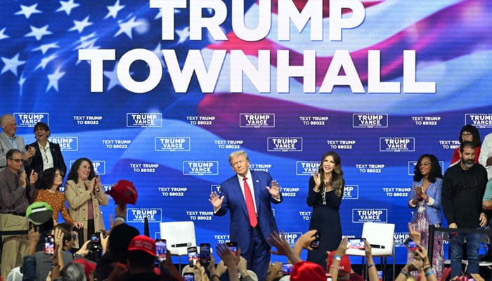 Former US President and Republican presidential candidate Donald Trump, with moderator and South Dakota Governor Kristi Noem (R), arrives for a town hall at the Greater Philadelphia Expo Center and Fairgrounds in Oaks, Pennsylvania, on October 14, 2024. — AFP