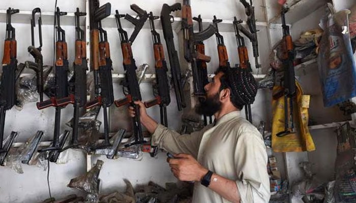 A representational image showing an arms dealer picking an assault rifle from a shelf at his shop in the tribal area of Darra Adamkhel. — AFP/File