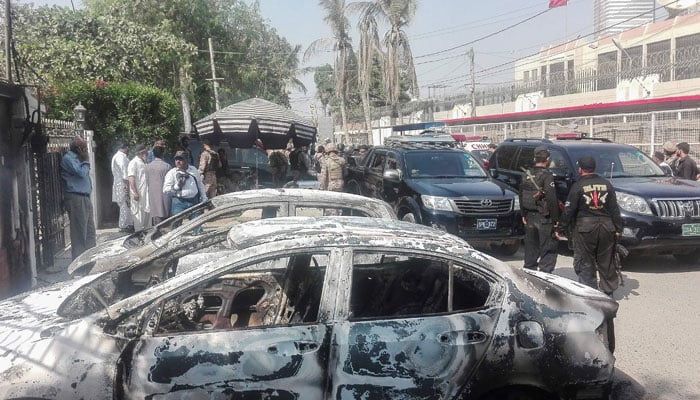 Pakistani security personnel stand next to burned-out vehicles in front of the Chinese consulate after an attack in Karachi on November 23, 2018. — AFP