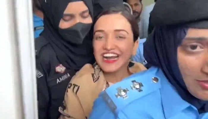 PTIs Sanam Javed can be seen smiling while being taken for court hearing on July 15, 2024 in Islamabad. — Screengrab via X/@MurtazaViews