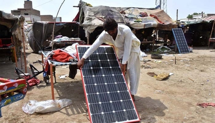 A man fixing a solar panel near his makeshift home in a slum. — Reuters/File