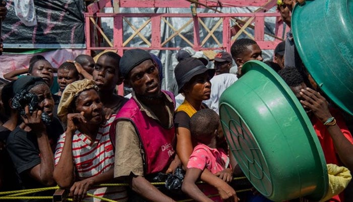 People wait for a food distribution in a displaced persons camp at the Lycée Marie Jeanne in Port-au-Prince on September 30, 2024. — AFP