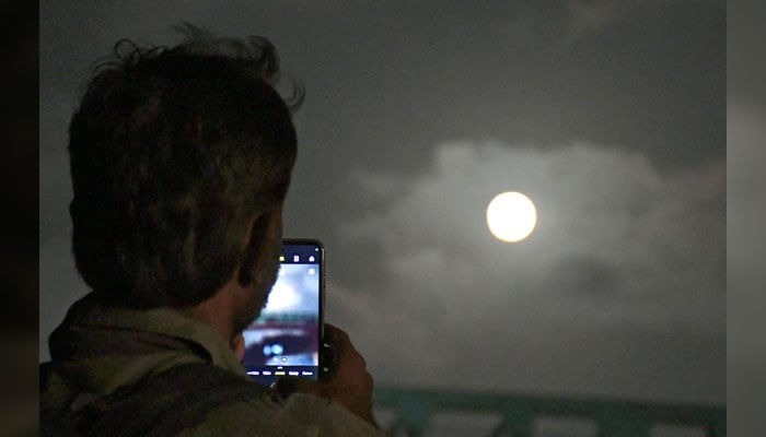 A man is taking a picture of Super moon, in Karachi on October 17, 2024. — Online