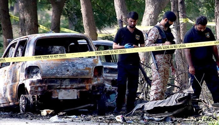 A view of the cordoned-off area where the wreckage of destroyed vehicles lies following a deadly explosion near Karachi airport on October 6, 2024. — APP