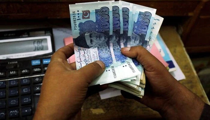 A trader counts Pakistani rupee notes at a currency exchange booth in Peshawar, Pakistan December 3, 2018. — Reuters