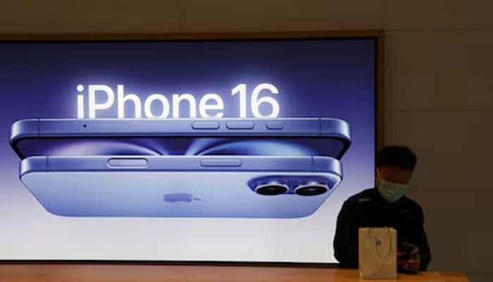 A man sits next to an iPhone 16 advertisement as the new iPhone 16 series smartphones go on sale at an Apple store in Beijing, China on September 20, 2024. — Reuters