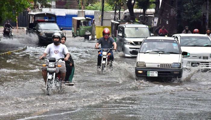 Vehicles on the way in the accumulated water on the road during heavy rain in Lahore on July 30, 2024. — APP