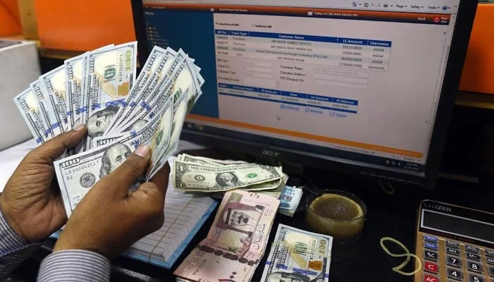 A foreign currency dealer counts US dollars at a shop in Karachi on May 19, 2022. — AFP