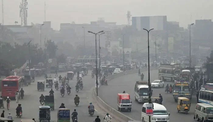 Representational image shows commuters making their way through a busy street amid smoggy conditions in Lahore. — AFP/File