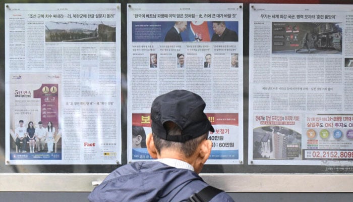 A man walks past a newspaper displayed on a street in Seoul with coverage on North Koreas decision to deploy thousands of soldiers to Russia.— AFP