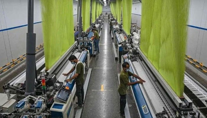 A worker operates a machine preparing fabric at the Kohinoor Textile Mills in Lahore on July 20, 2023. — AFP