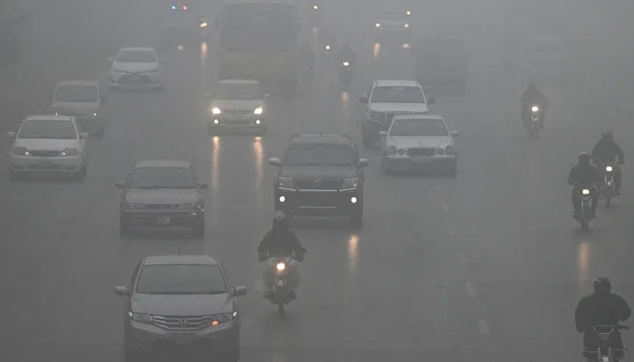 Commuters make their way along a road amid dense smog in Islamabad on January 22, 2024. — AFP