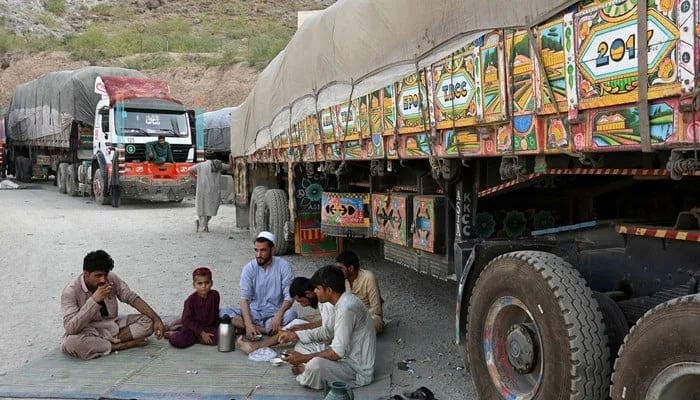 In this representational image drivers along with a boy drinking tea next to trucks. — AFP/File