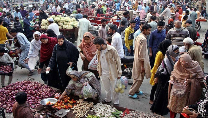 People buy vegetables at a local market located in Tajpura area in Lahore on December 3, 2023. — AFP