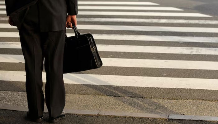 Representational image shows a businessman waiting to cross a street in Tokyo on April 4, 2011. — Reuters