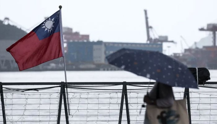 A woman walks past a Taiwanese national flag at Maritime Plaza in Keelung, Taiwan. — AFP/file