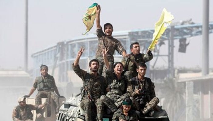 Kurdish-led militiamen ride atop a vehicles as they celebrate a military victory in Syria. — Reuters/File