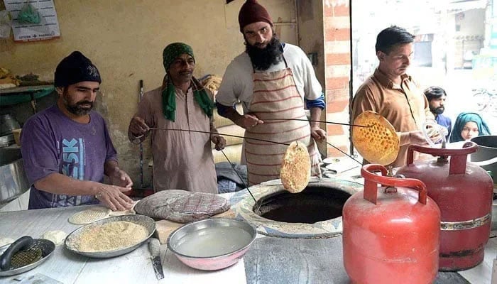 A representational image of a vendor is seen busy making traditional bread (Naan) at a tandoor. — APP/File