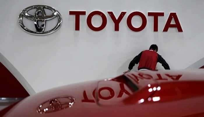 An employee works under a Toyota Motor Corp logo at the companys showroom. — Reuters/File