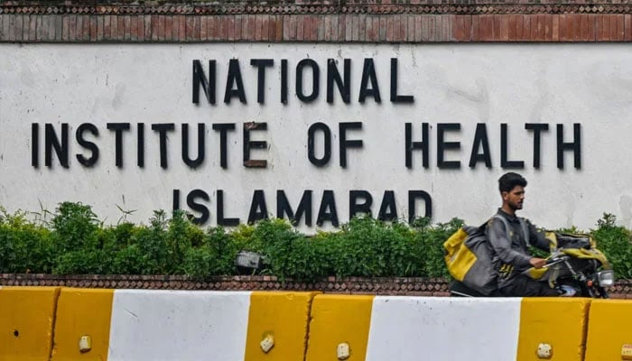 A delivery boy rides past the National Institute of Health (NIH) building in Islamabad on August 16, 2024. — AFP