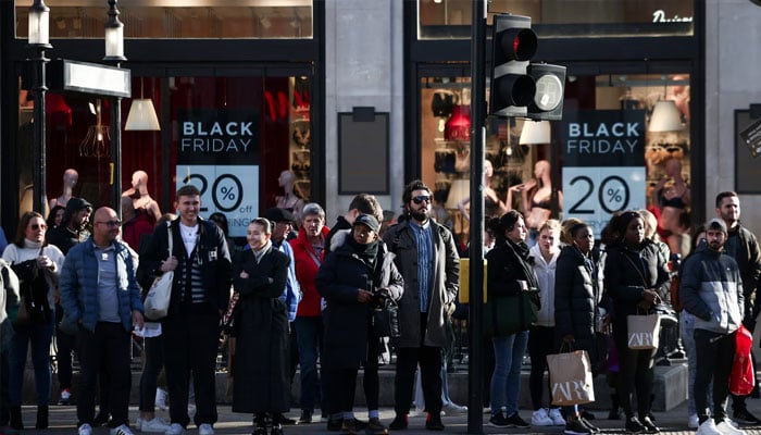 People stand near Black Friday signage in shop windows during Black Friday on Oxford Street in London, Britain, November 25, 2022. — Reuters