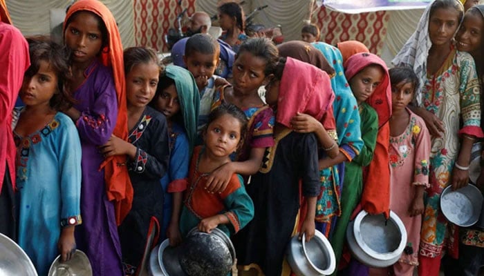 Flood victims gather to receive food handout in a camp following rains and floods during the monsoon season in Sehwan on September 14, 2022. — Reuters