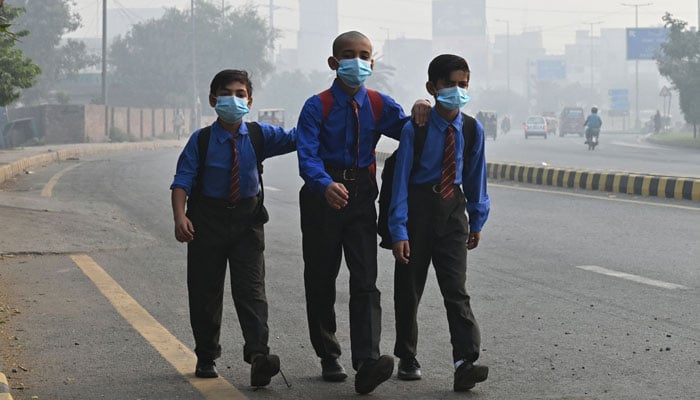 School boys wear masks as they walk along a road amid heavy smog in Lahore on October 29, 2024. — AFP