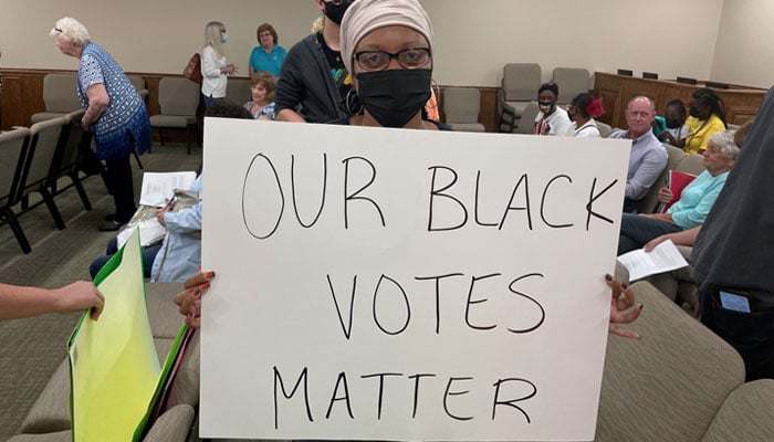 Yoshunda Jones, a local activist who protested the elimination of Sunday voting, holds up a sign in Spalding County, Georgia, US, October 12, 2021. — Reuters