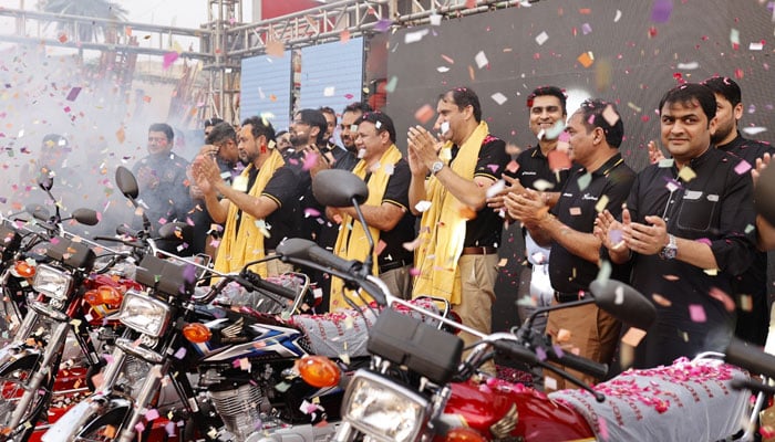 People claping on launch of a new model motor bike. — Facebook@Atlas.Honda.pk