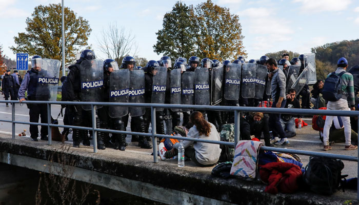 Bosnia police stand guard in front of migrants at Maljevac border crossing between Bosnia and Croatia near Velika Kladusa, Bosniaon   on October 24, 2018. — Reuters