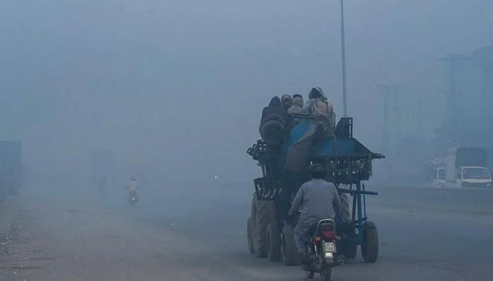 People commute along a street amid heavy smoggy conditions in Lahore. — AFP/File