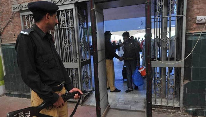 In this representational image, Pakistan Railway police personnel check passengers at the railway station entrance. — AFP/File