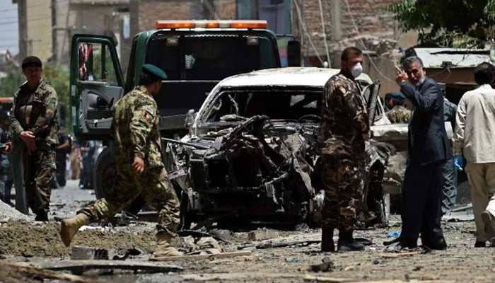 Afghan security forces inspect a damaged vehicle at the site of a bomb blast.— AFP/File