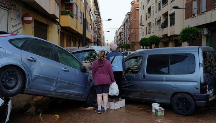 Residents stand in front of piled up cars following deadly floods in Alfafar neighbourhood, south of Valencia. — AFP/File