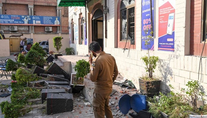 In this photograph taken on October 16, 2024, a police personnel walks through a college premises, vandalised during a protest to condemn the alleged rape of a woman student, in Lahore. — AFP