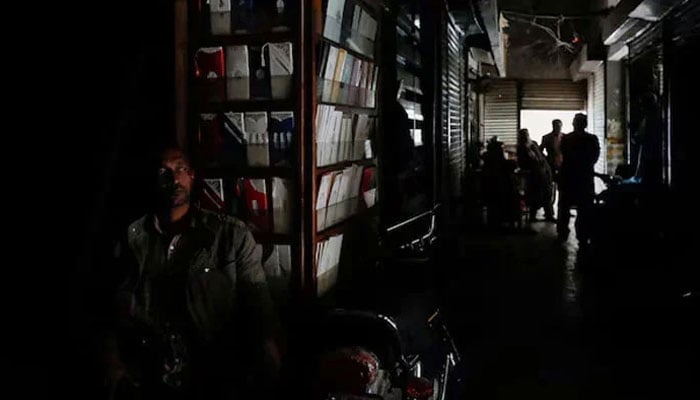 A man sits outside his shop during a power breakdown in Pakistan. — Reuters/File