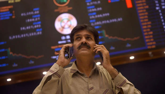 An investor talking on phone infront of  the screen in this undated picture. — AFP/File