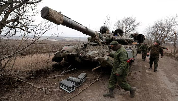 Pro-Russian separatists walk near an abandoned tank on a road between the separatist-controlled settlements of Mykolaivka (Nikolaevka) and Buhas (Bugas). — Reuters/File